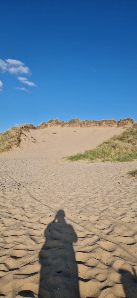 Shadow of a figure walking on a sandy beach